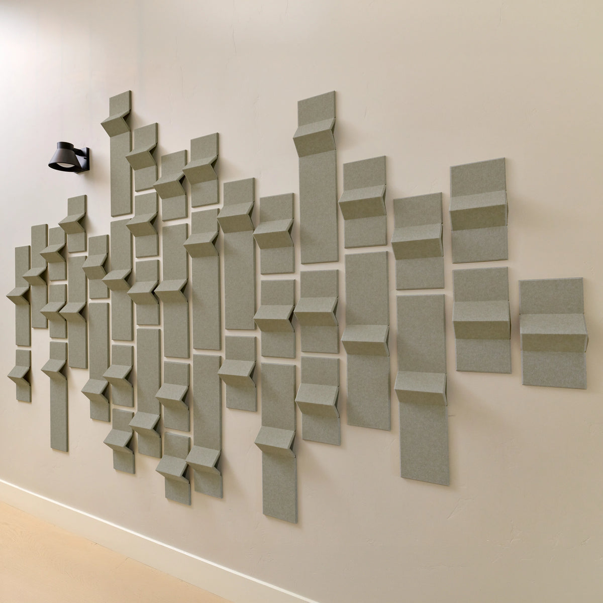 Soft green acoustic felt tiles with peaks of dimension along a wall