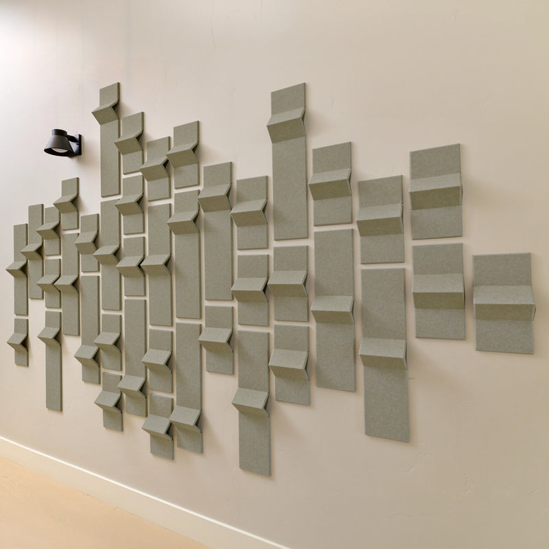 Soft green acoustic felt tiles with peaks of dimension along a wall