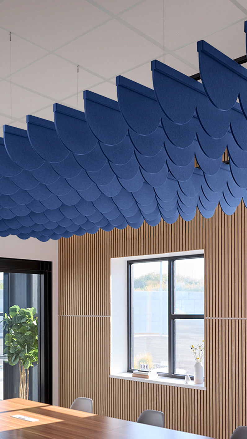 Blue acoustic ceiling blade baffles suspended from the ceiling, installed in a conference room. Felt Right's acoustic blade baffles absorb 65% of sound waves, making office spaces quieter and feel more calm.
