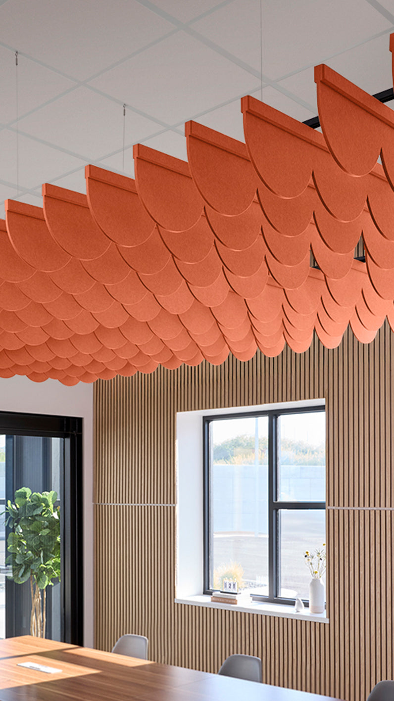 Orange acoustic ceiling blade baffles suspended from the ceiling, installed in a conference room. Felt Right's acoustic blade baffles absorb 65% of sound waves, making office spaces quieter and feel more calm.