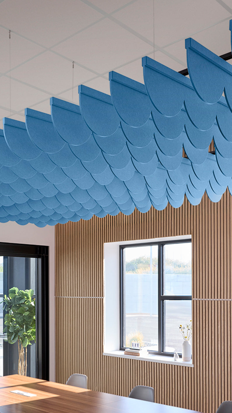 Bright blue acoustic ceiling blade baffles suspended from the ceiling, installed in a conference room. Felt Right's acoustic blade baffles absorb 65% of sound waves, making office spaces quieter and feel more calm.