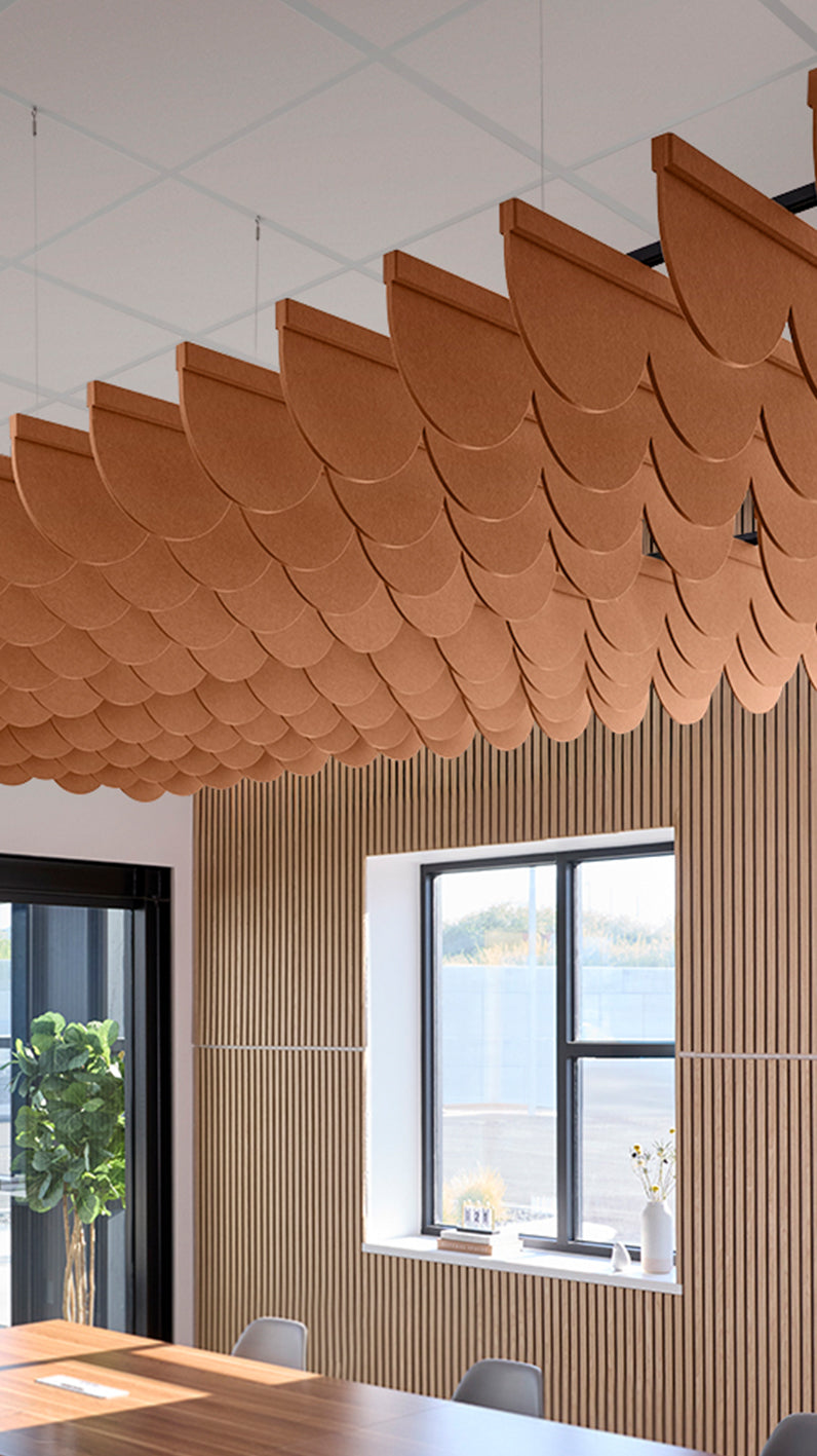 Dark orange acoustic ceiling blade baffles suspended from the ceiling, installed in a conference room. Felt Right's acoustic blade baffles absorb 65% of sound waves, making office spaces quieter and feel more calm.