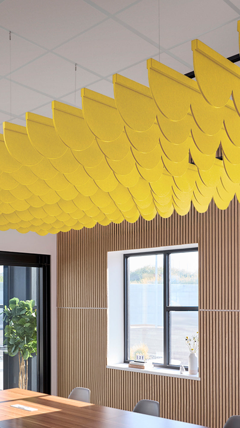 Yellow acoustic ceiling blade baffles suspended from the ceiling, installed in a conference room. Felt Right's acoustic blade baffles absorb 65% of sound waves, making office spaces quieter and feel more calm.
