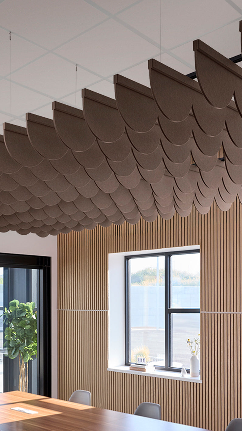 Brown acoustic ceiling blade baffles suspended from the ceiling, installed in a conference room. Felt Right's acoustic blade baffles absorb 65% of sound waves, making office spaces quieter and feel more calm.