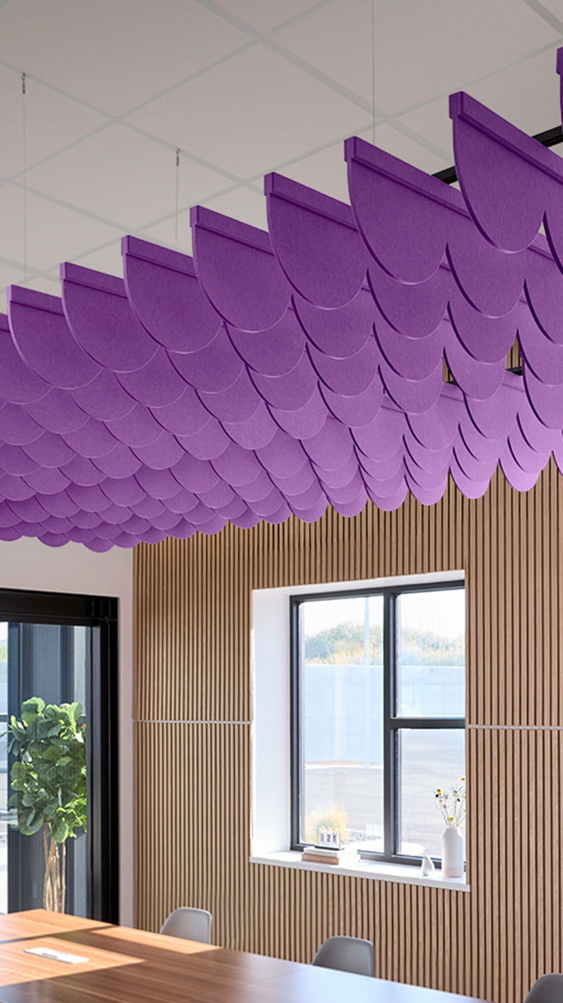 Purple acoustic ceiling blade baffles suspended from the ceiling, installed in a conference room. Felt Right's acoustic blade baffles absorb 65% of sound waves, making office spaces quieter and feel more calm.