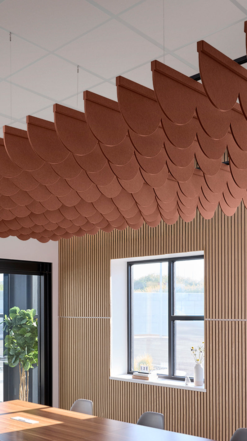 Reddish-brown acoustic ceiling blade baffles suspended from the ceiling, installed in a conference room. Felt Right's acoustic blade baffles absorb 65% of sound waves, making office spaces quieter and feel more calm.