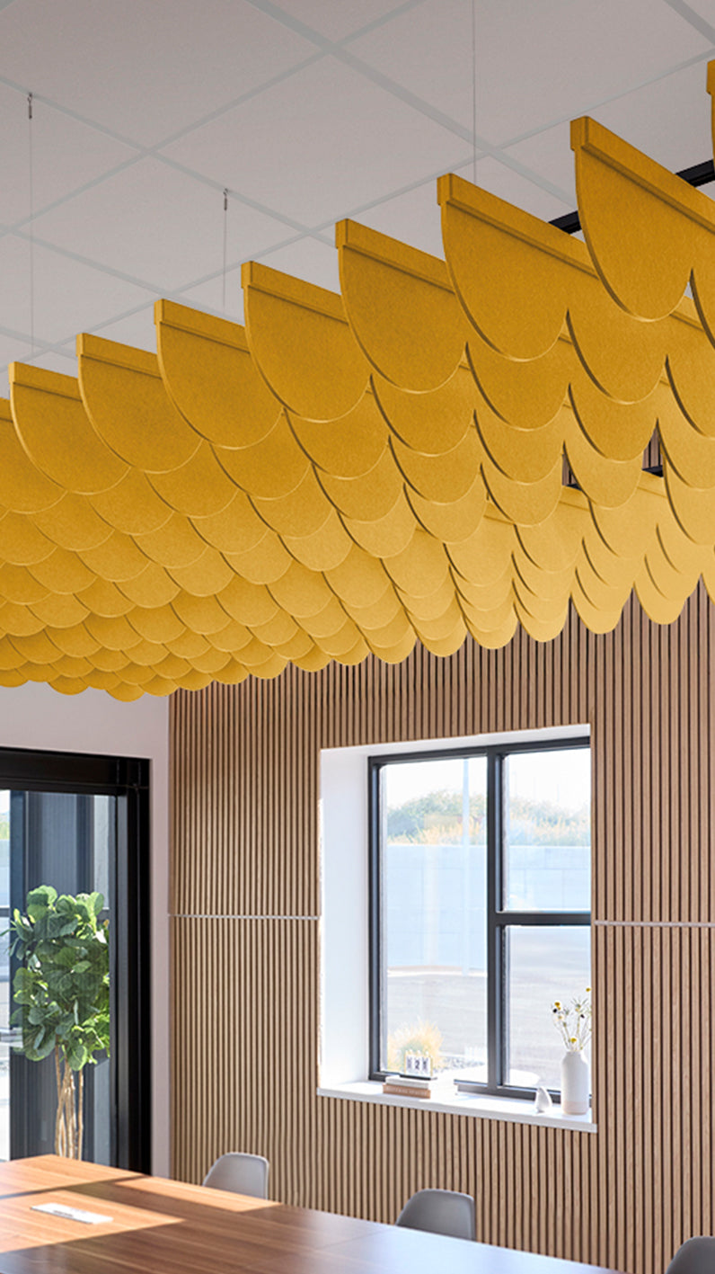 Dark yellow acoustic ceiling blade baffles suspended from the ceiling, installed in a conference room. Felt Right's acoustic blade baffles absorb 65% of sound waves, making office spaces quieter and feel more calm.