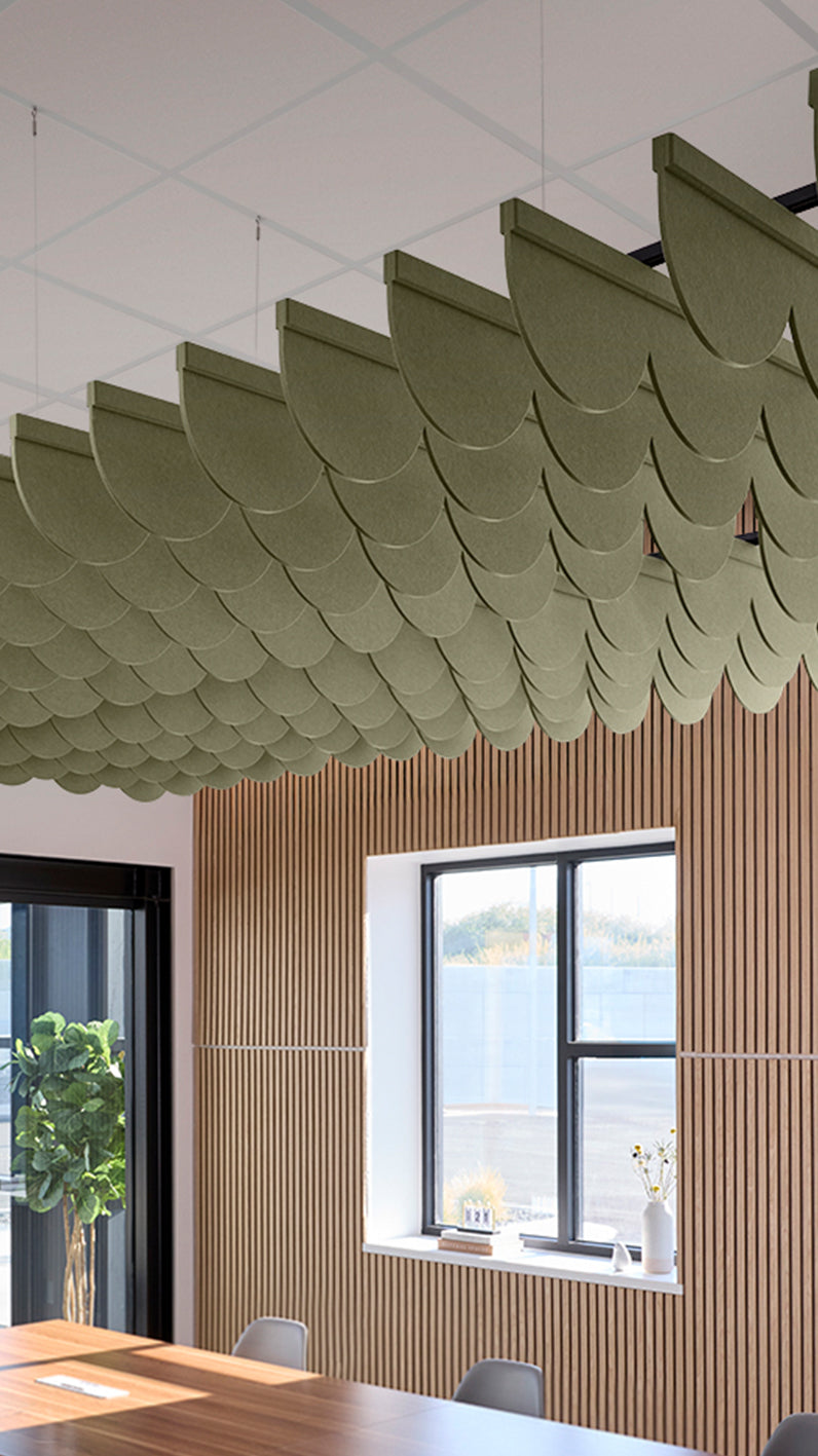 Green acoustic ceiling blade baffles suspended from the ceiling, installed in a conference room. Felt Right's acoustic blade baffles absorb 65% of sound waves, making office spaces quieter and feel more calm.