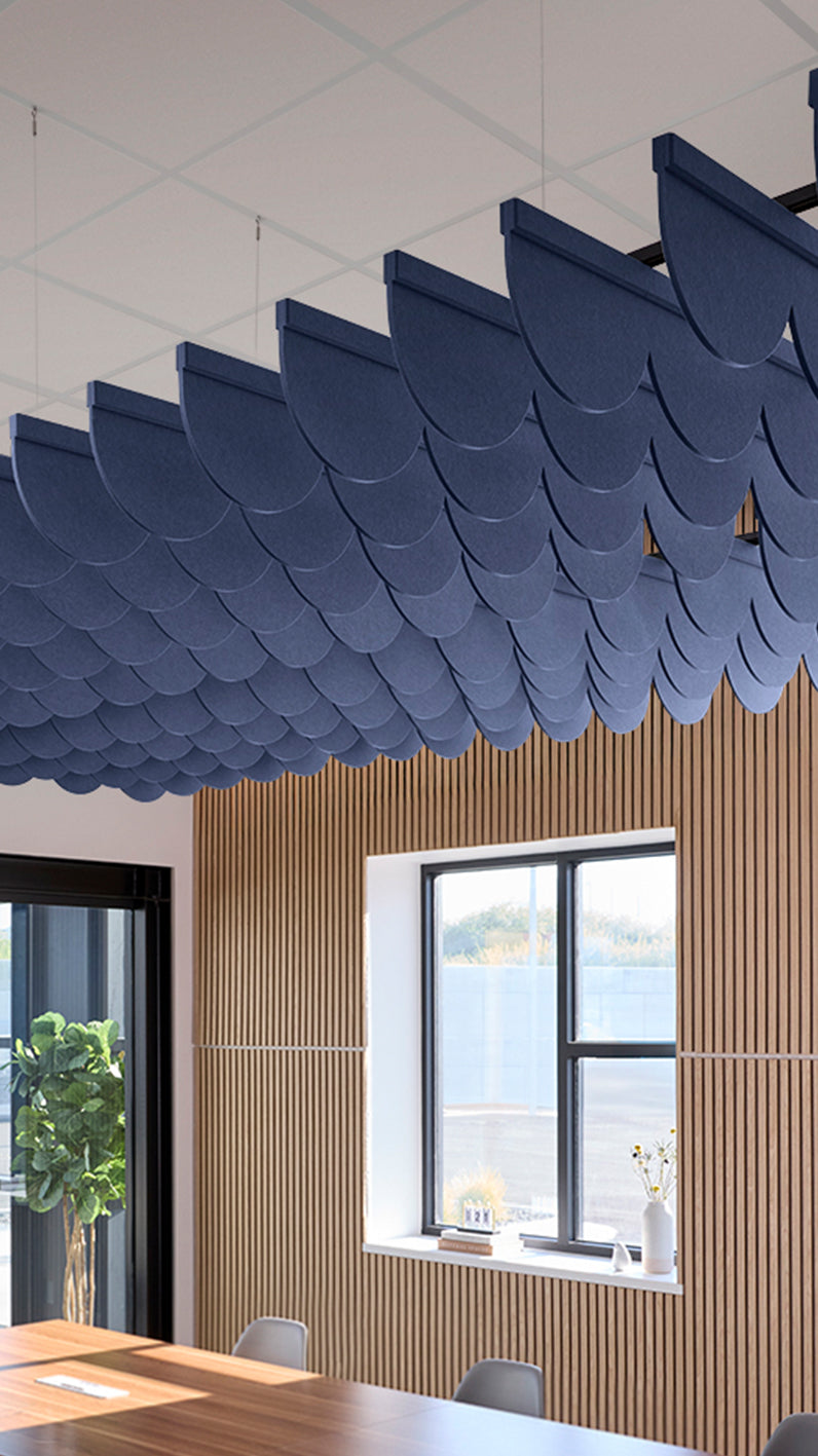 Dark blue acoustic ceiling blade baffles suspended from the ceiling, installed in a conference room. Felt Right's acoustic blade baffles absorb 65% of sound waves, making office spaces quieter and feel more calm.