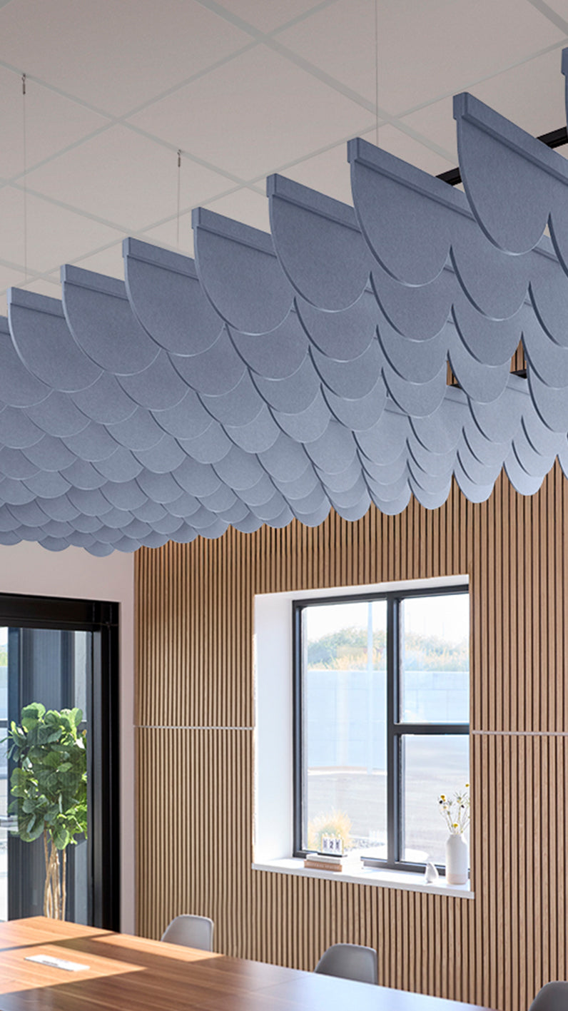 Purplish-blue acoustic ceiling blade baffles suspended from the ceiling, installed in a conference room. Felt Right's acoustic blade baffles absorb 65% of sound waves, making office spaces quieter and feel more calm.
