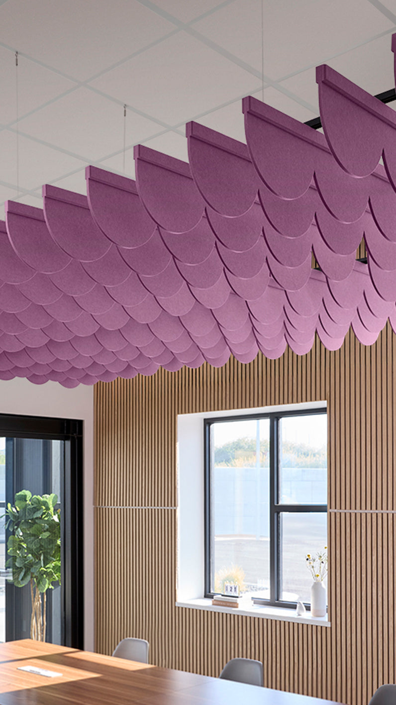 Reddish-purple acoustic ceiling blade baffles suspended from the ceiling, installed in a conference room. Felt Right's acoustic blade baffles absorb 65% of sound waves, making office spaces quieter and feel more calm.