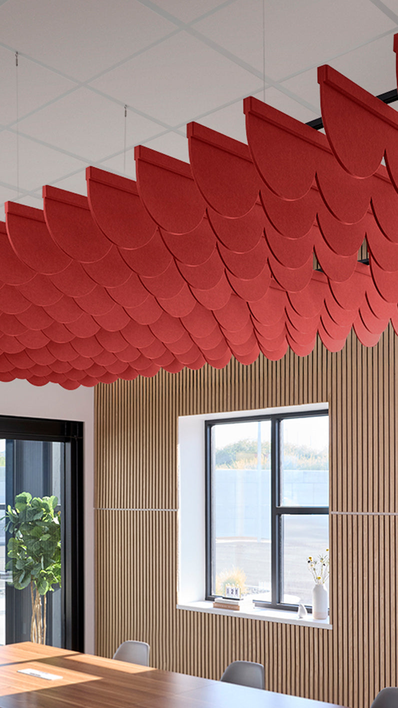 Bright red acoustic ceiling blade baffles suspended from the ceiling, installed in a conference room. Felt Right's acoustic blade baffles absorb 65% of sound waves, making office spaces quieter and feel more calm.