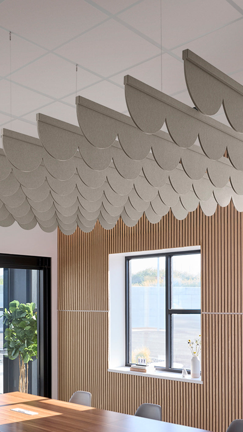 Light brownish-grey acoustic ceiling blade baffles suspended from the ceiling, installed in a conference room. Felt Right's acoustic blade baffles absorb 65% of sound waves, making office spaces quieter and feel more calm.