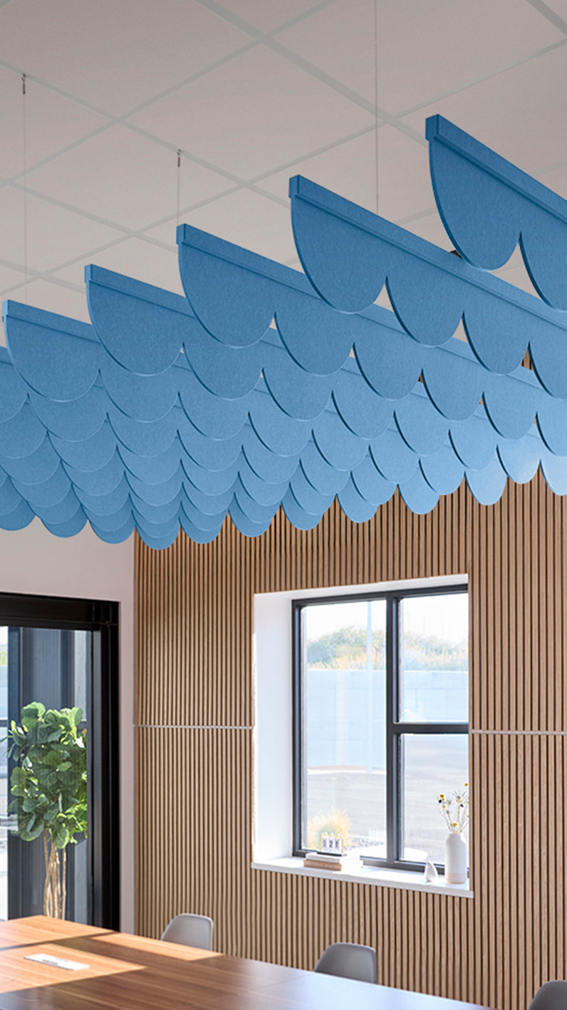 Bright blue acoustic ceiling blade baffles suspended from the ceiling, installed in a conference room. Felt Right's acoustic blade baffles absorb 65% of sound waves, making office spaces quieter and feel more calm.