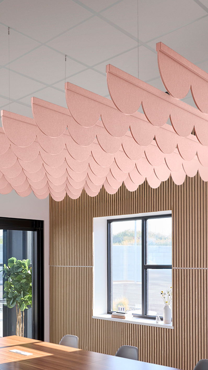 Soft pink acoustic ceiling blade baffles suspended from the ceiling, installed in a conference room. Felt Right's acoustic blade baffles absorb 65% of sound waves, making office spaces quieter and feel more calm.