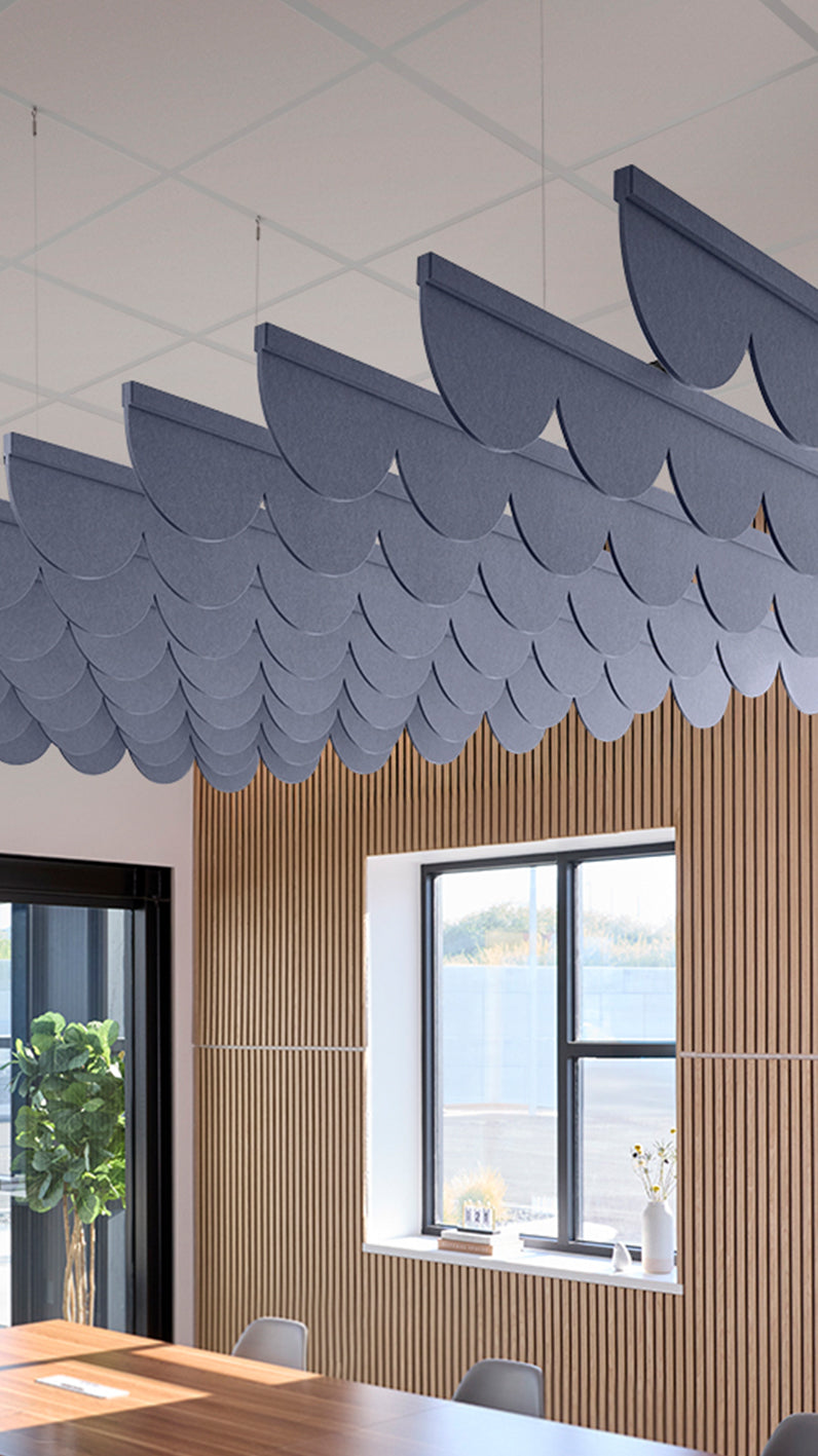 Indigo blue acoustic ceiling blade baffles suspended from the ceiling, installed in a conference room. Felt Right's acoustic blade baffles absorb 65% of sound waves, making office spaces quieter and feel more calm.