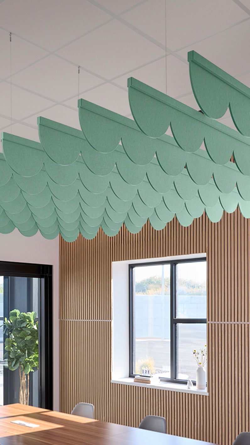 Mint green acoustic ceiling blade baffles suspended from the ceiling, installed in a conference room. Felt Right's acoustic blade baffles absorb 65% of sound waves, making office spaces quieter and feel more calm.