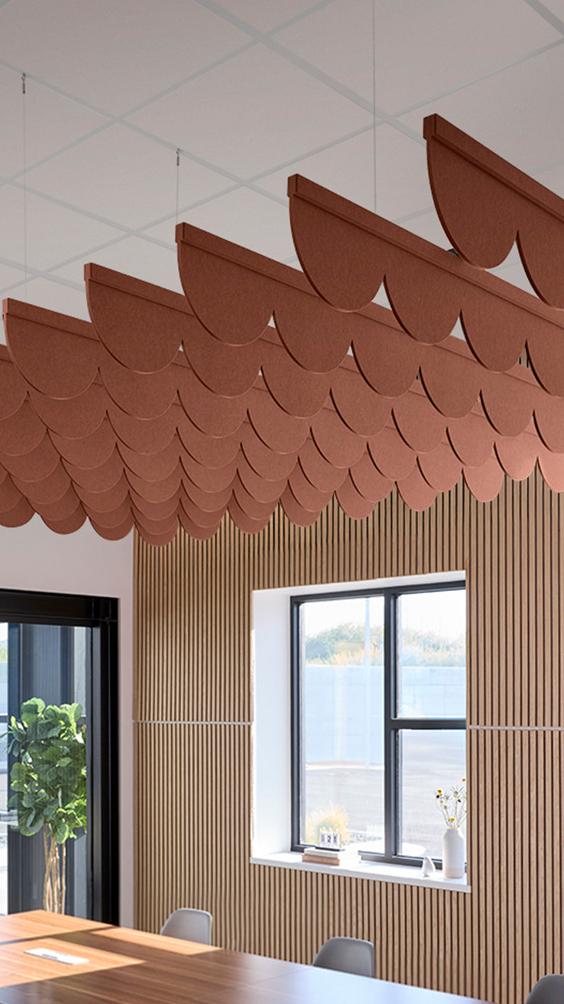 Reddish-brown acoustic ceiling blade baffles suspended from the ceiling, installed in a conference room. Felt Right's acoustic blade baffles absorb 65% of sound waves, making office spaces quieter and feel more calm.