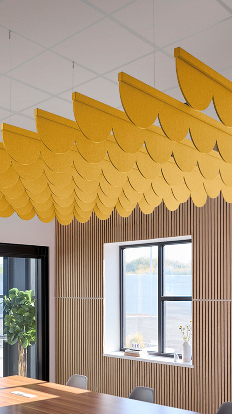 Dark yellow acoustic ceiling blade baffles suspended from the ceiling, installed in a conference room. Felt Right's acoustic blade baffles absorb 65% of sound waves, making office spaces quieter and feel more calm.