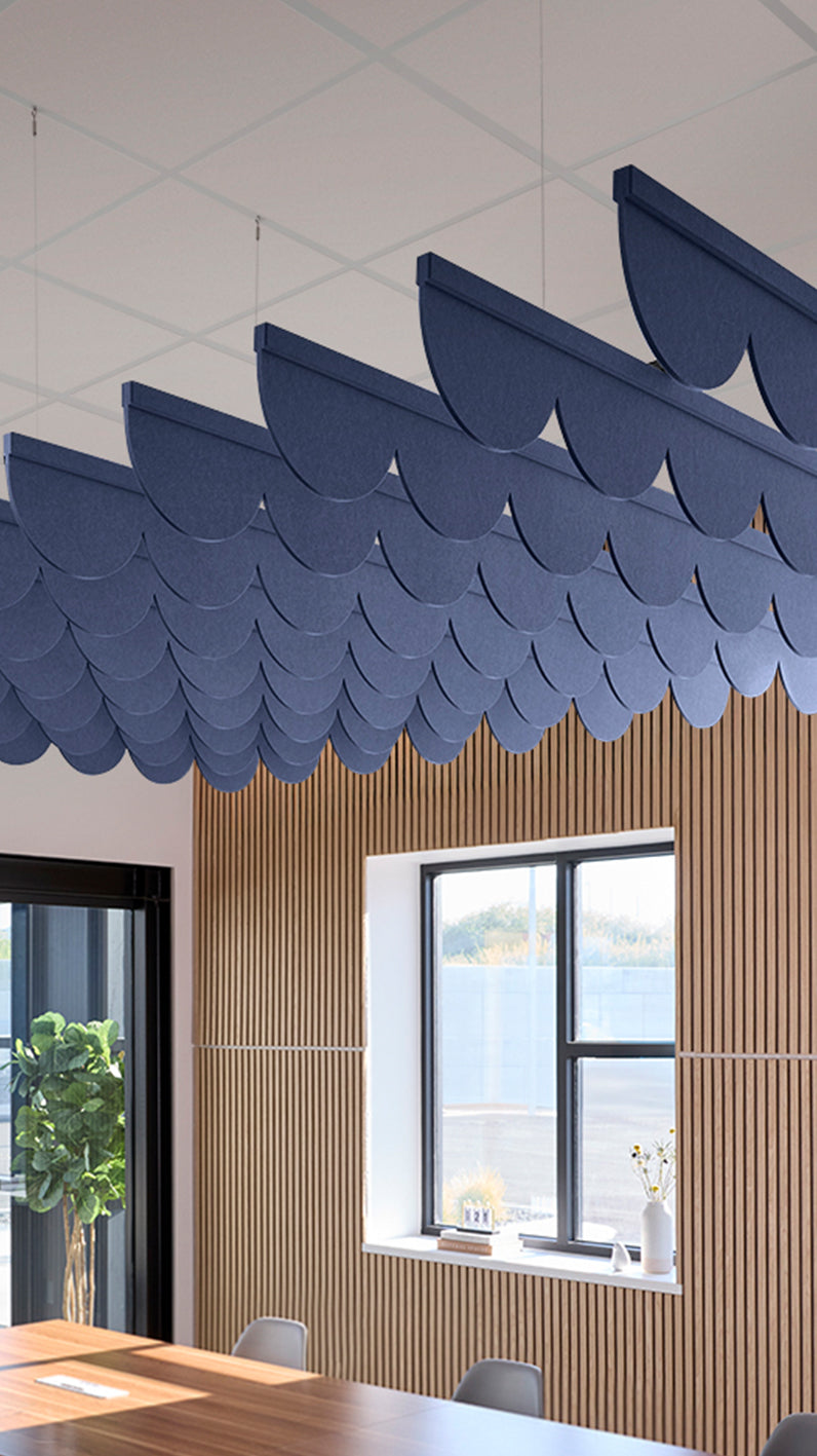 Dark blue acoustic ceiling blade baffles suspended from the ceiling, installed in a conference room. Felt Right's acoustic blade baffles absorb 65% of sound waves, making office spaces quieter and feel more calm.