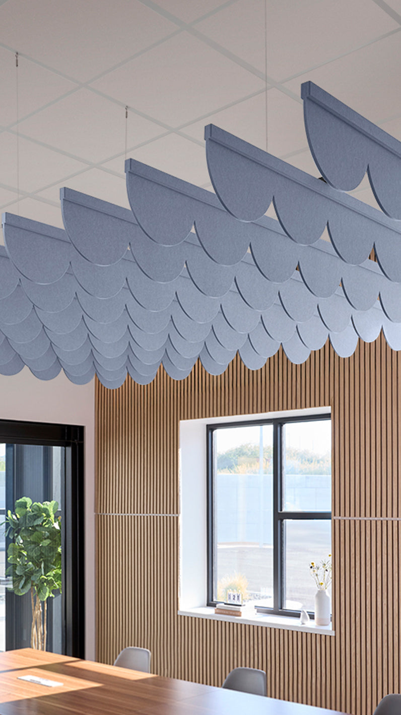 Purplish blue acoustic ceiling blade baffles suspended from the ceiling, installed in a conference room. Felt Right's acoustic blade baffles absorb 65% of sound waves, making office spaces quieter and feel more calm.