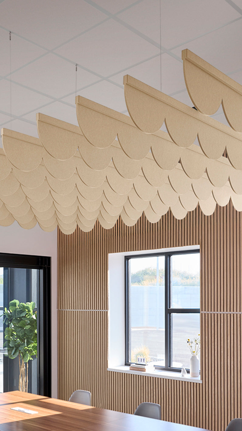 Light tan acoustic ceiling blade baffles suspended from the ceiling, installed in a conference room. Felt Right's acoustic blade baffles absorb 65% of sound waves, making office spaces quieter and feel more calm.