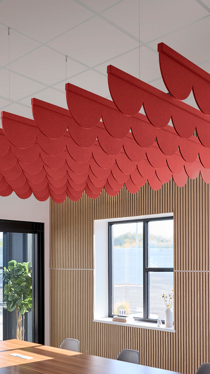 Bright red acoustic ceiling blade baffles suspended from the ceiling, installed in a conference room. Felt Right's acoustic blade baffles absorb 65% of sound waves, making office spaces quieter and feel more calm.
