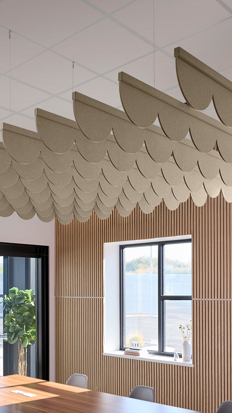 Light brown acoustic ceiling blade baffles suspended from the ceiling, installed in a conference room. Felt Right's acoustic blade baffles absorb 65% of sound waves, making office spaces quieter and feel more calm.