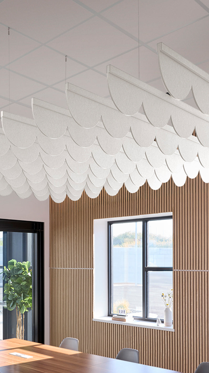 White acoustic ceiling blade baffles suspended from the ceiling, installed in a conference room. Felt Right's acoustic blade baffles absorb 65% of sound waves, making office spaces quieter and feel more calm.