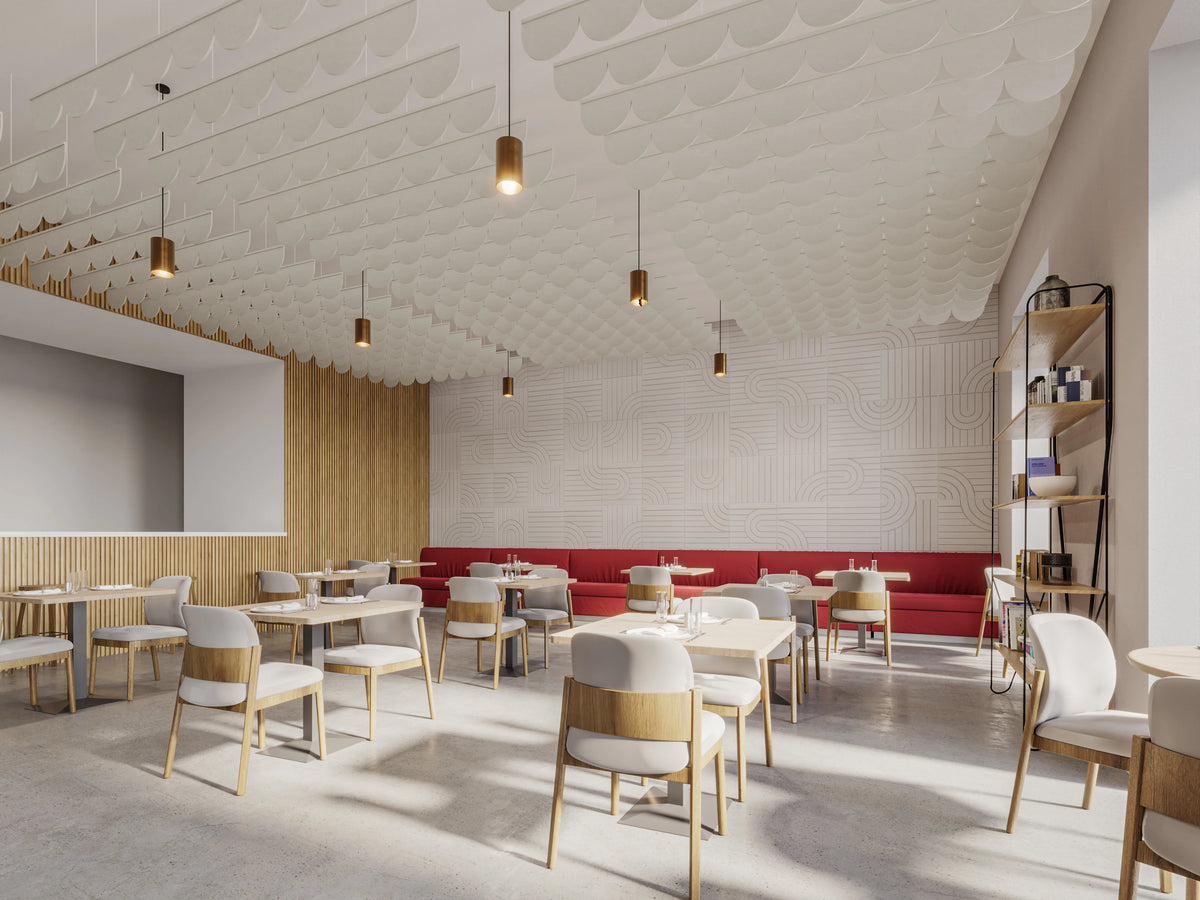 A modern dining room or cafe interior with multiple light wood chairs, white upholstered seats, and small round tables arranged in rows. A long red upholstered counter or sofa runs along one wall, and the ceiling has a textured white patterned design with hanging cylindrical pendant lights.