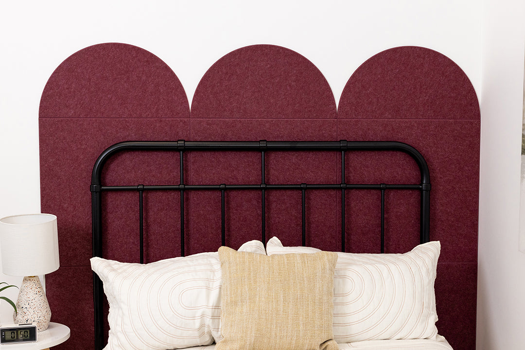 A Felt Right wall design as a head board for a bed in a bedroom in shade of dark red.