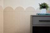 Beige scallop wainscoting with vertical paneling and rounded top molding on wall above furniture.