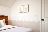 Cream-colored wainscoting with scalloped top edge installed on bedroom wall below white painted upper wall.