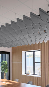 Gray scallop-shaped acoustic baffles suspended from ceiling in overlapping rows above wooden wall paneling.