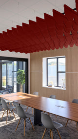 Red scallop-shaped acoustic baffle panels suspended from ceiling above conference table in modern office space.