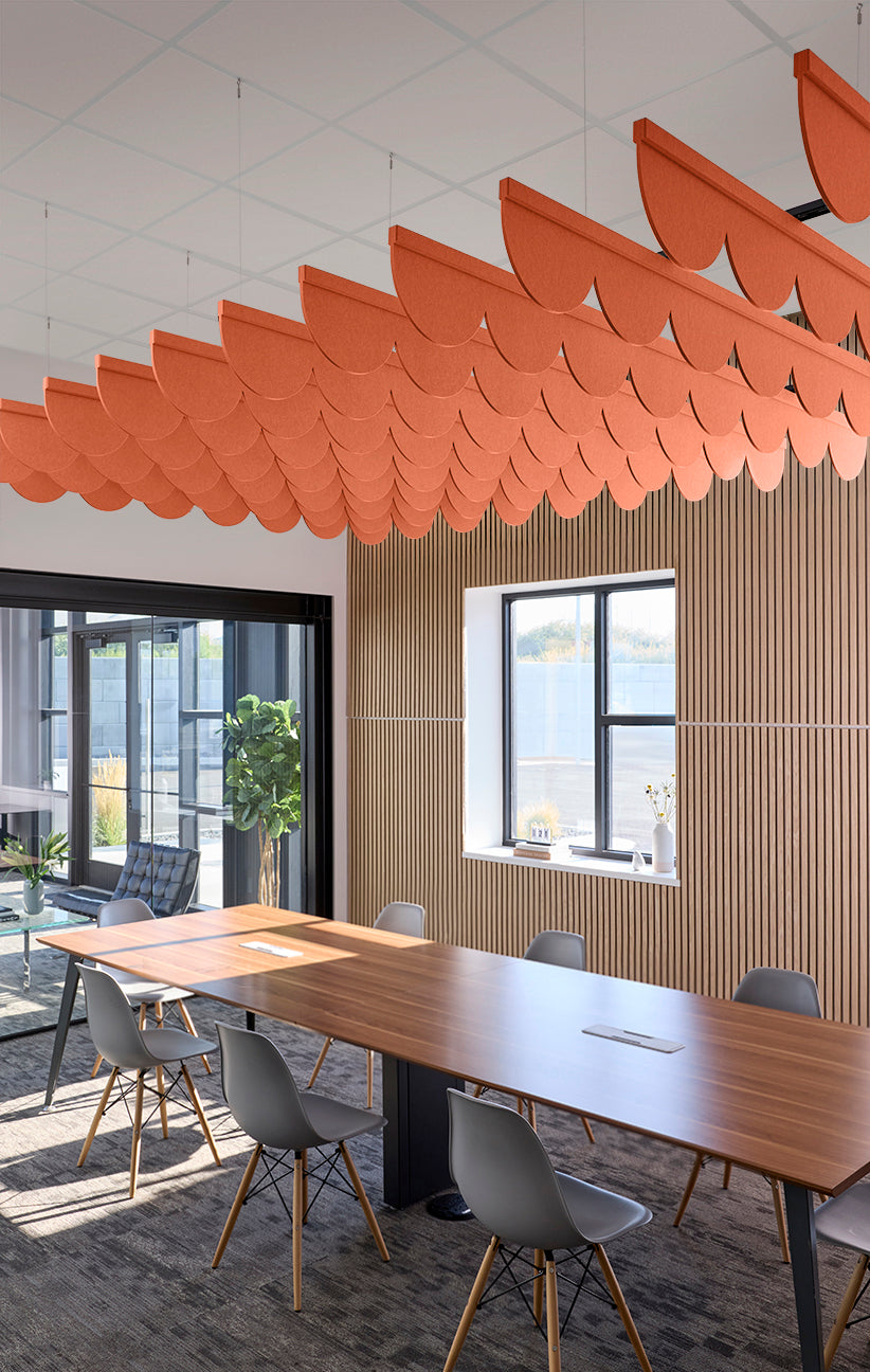 Orange scallop-shaped acoustic baffles suspended from ceiling in office conference room.