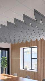 Gray scalloped acoustic baffles suspended from ceiling grid above wood-slat wall paneling in office space.