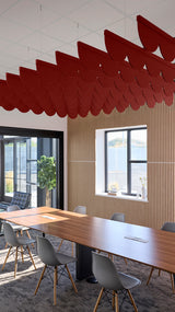 Red scallop-shaped acoustic baffles suspended from ceiling in modern office conference room.
