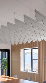 Gray scalloped acoustic baffles suspended from ceiling in office space above wooden wall paneling.