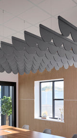 Gray scallop-shaped acoustic baffles suspended from ceiling above wood-paneled wall with window.