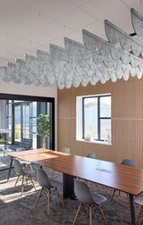 A modern conference room with a long wooden table, gray chairs, a slatted wood wall, and a large decorative cloud-shaped hanging light fixture suspended from the ceiling.