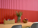 Hot pink and scarlet vertical louvered wall panels with woven basket, glass vase with greenery, and wooden bowl on wooden tab