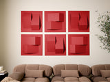 Six red dimensional tiles with geometric cutout patterns arranged in a grid on a wall above a tan sectional sofa.