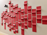 Red dimensional tiles arranged in a staggered pattern on a beige wall, creating a three-dimensional textured display.