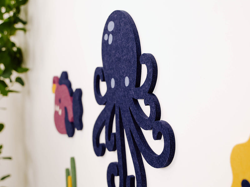 Decorative cutout of an octopus on a white wall with plants in the background