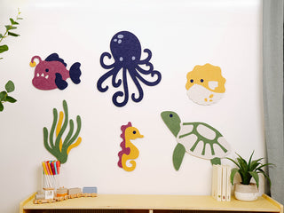 Wall decorations of sea creatures on a white wall with a shelf below.