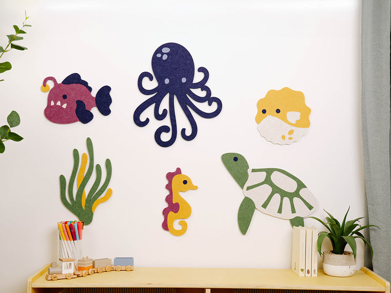 Wall decorations of sea creatures on a white wall with a shelf below.