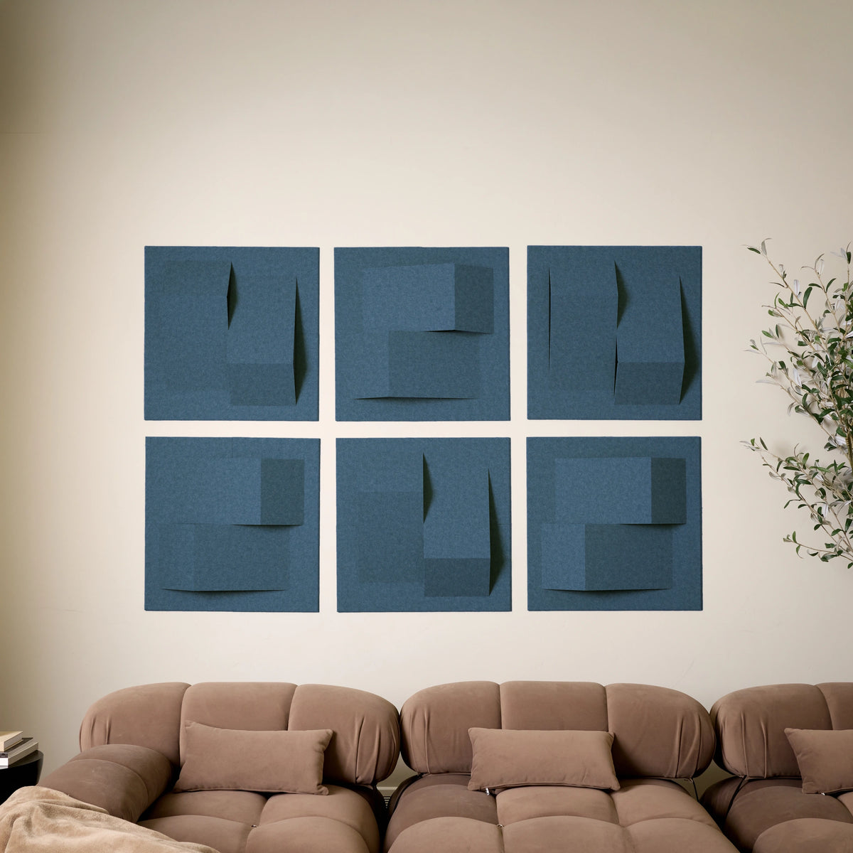 Six blue felt acoustic tiles in a 3D peak design above a sofa