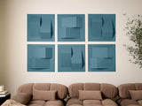 Six teal tiles with geometric cutouts and dimensional shapes arranged in a grid on a beige wall above a tan sofa.