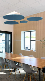 Four teal elliptical acoustic baffles suspended from ceiling in modern conference room above wooden table.